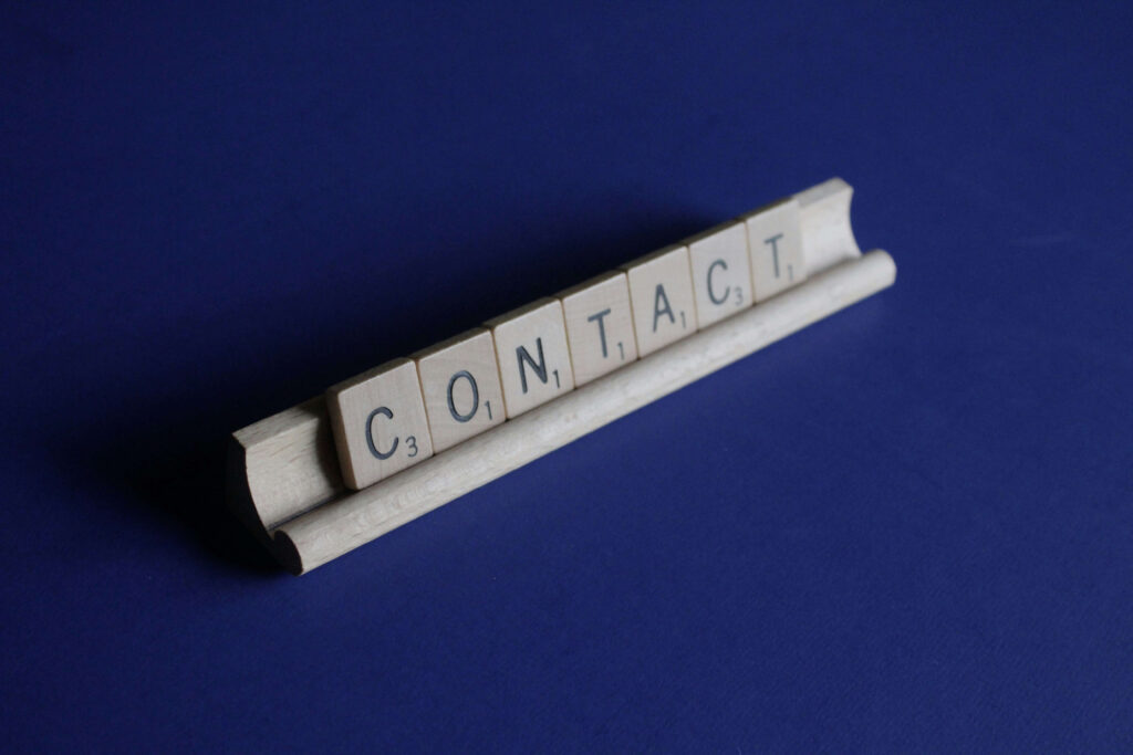 Une image qui montre des lettres de scrabble, et qui forme le mot "contact".